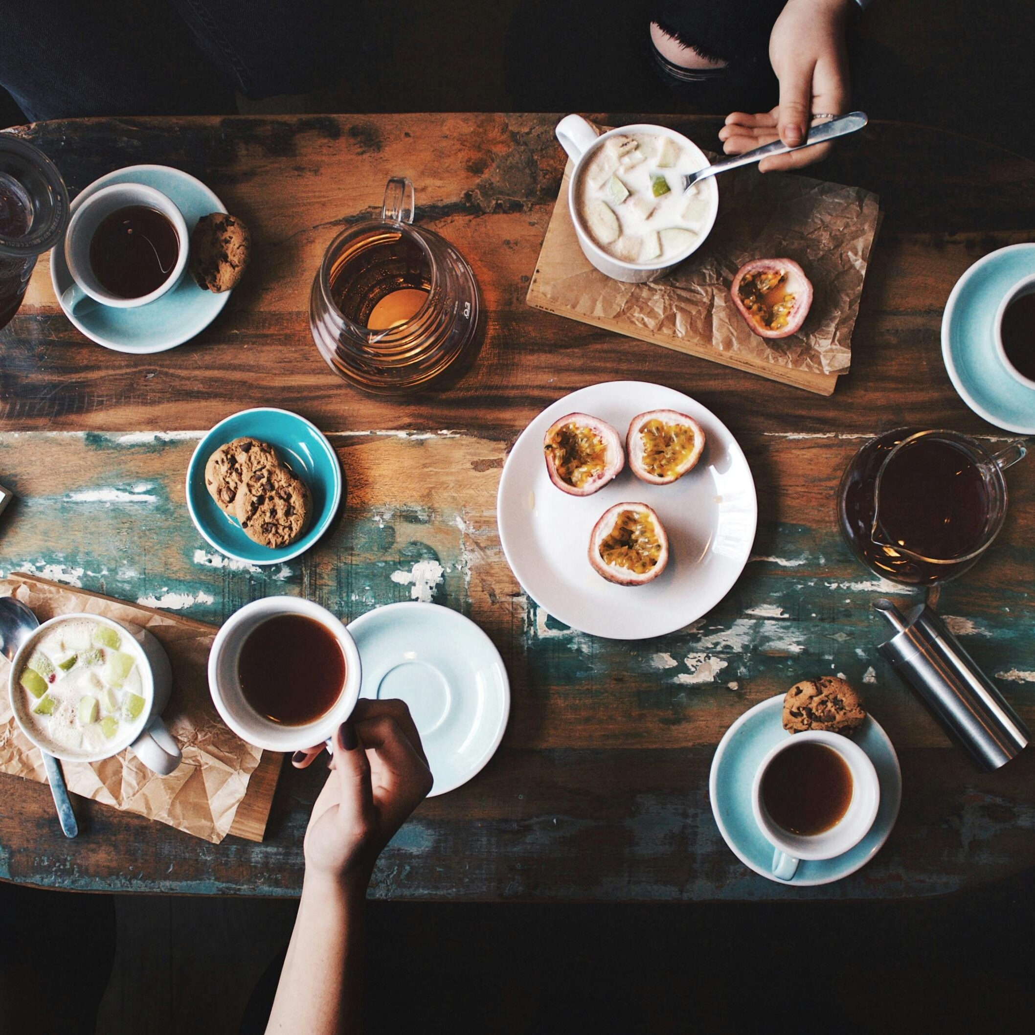Overhead view of a cozy coffee table setup with cups, snacks, and books, perfect for a relaxing afternoon.
